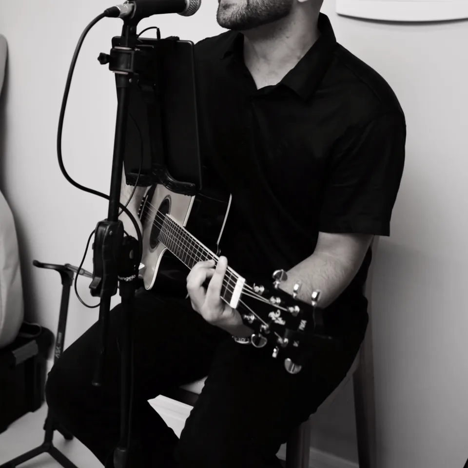 Detalhe de voz, violão e microfone durante apresentação acústica