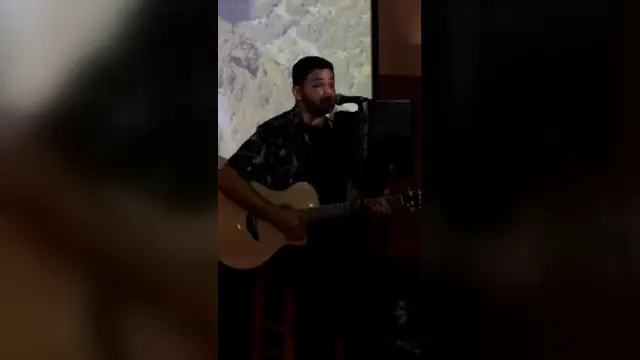 AQUINO cantando e tocando violão no vídeo Fly Me to the Moon, de Frank Sinatra