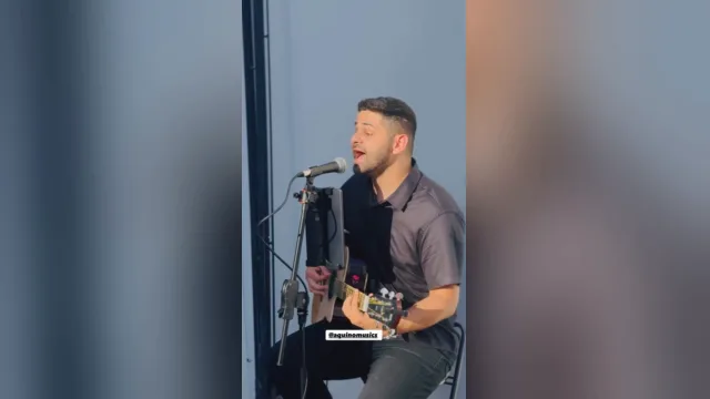 AQUINO cantando e tocando violão no vídeo Pescador, de Armandinho