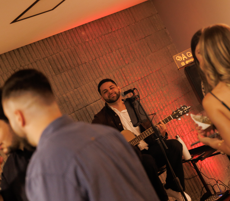 Músico Aquino tocando voz e violão ao vivo em um casamento intimista.